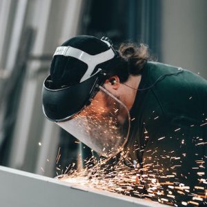 Worker with a clear mask on with sparks flying - SCR Safety Solutions